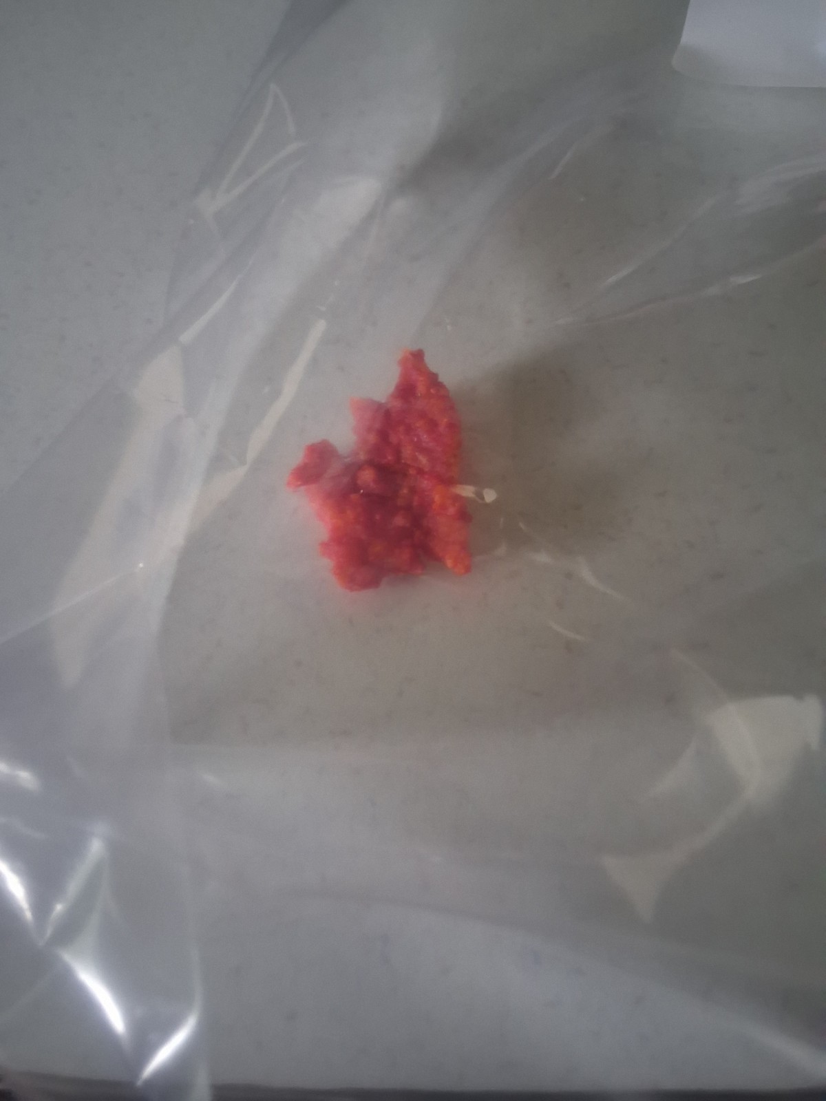 Single Red Puffed Snack Piece in Clear Plastic Bag