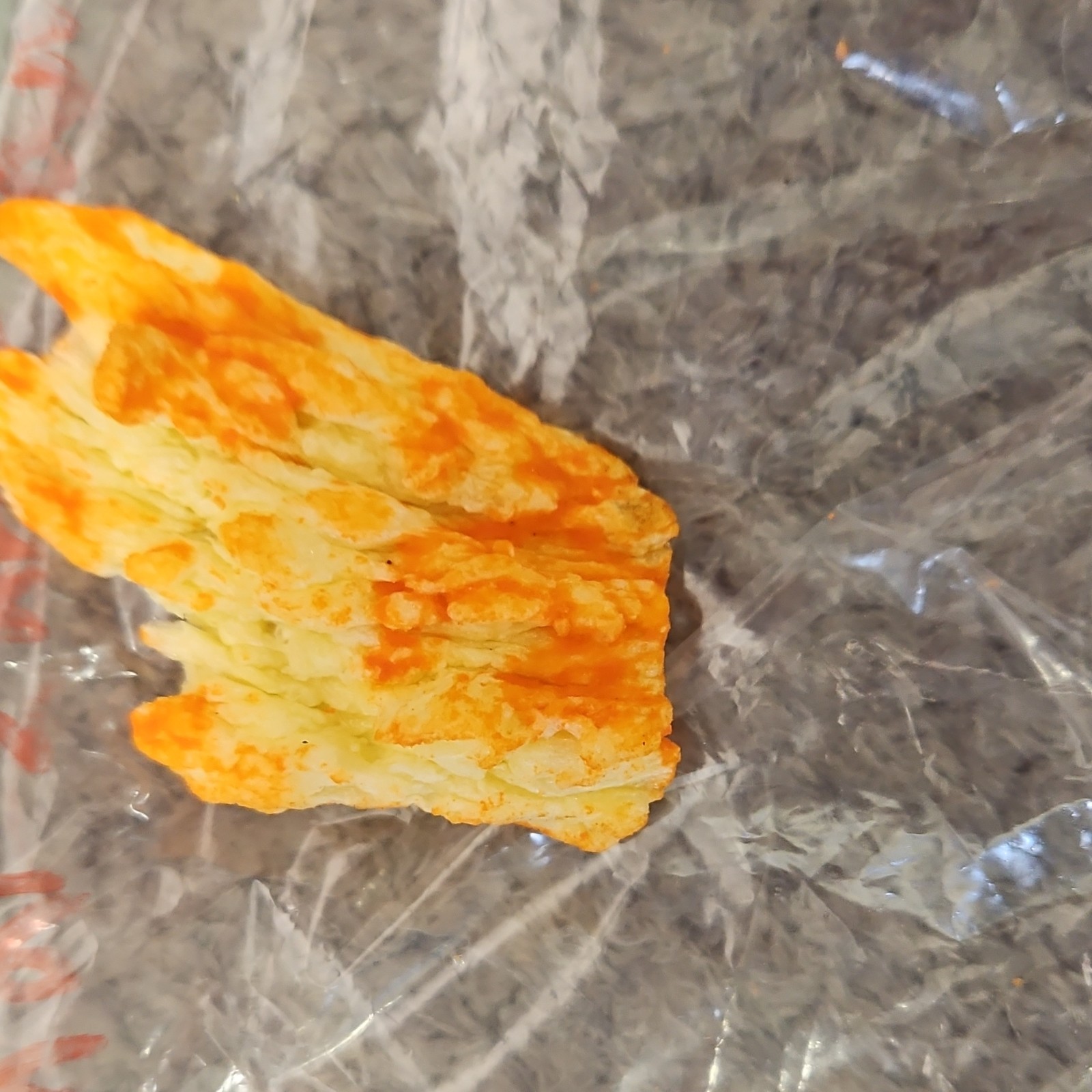 Single Cheese-Flavored Puffed Snack Piece (Cheetos-Style) in Plastic Bag