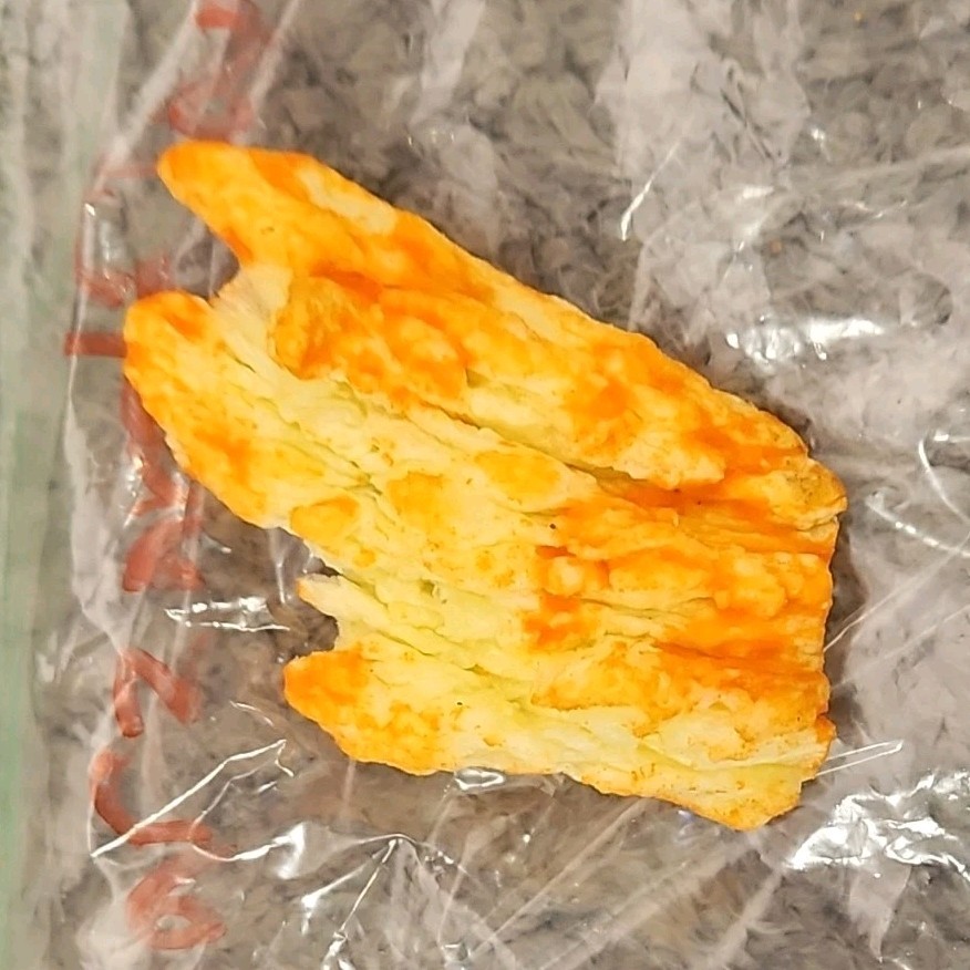 Single Cheese-Flavored Puffed Snack Piece (Cheetos-Style) in Plastic Bag